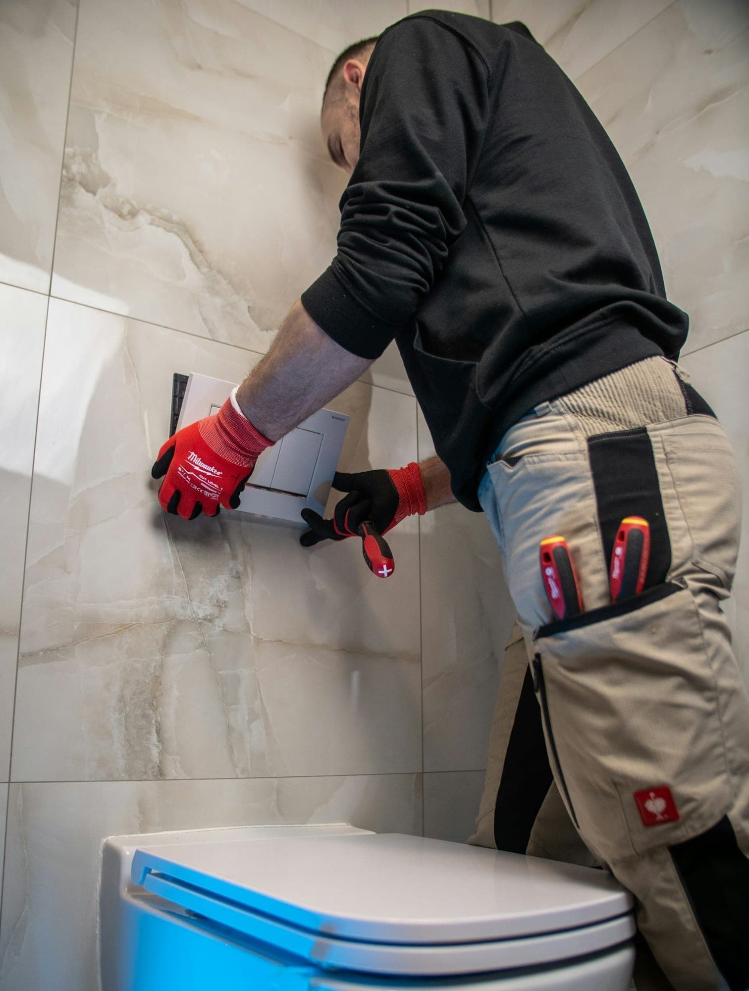 Plumber in red gloves repairing a toilet